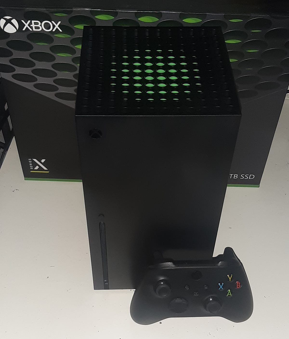 Console Xbox Series X com o controle, diante da caixa do aparelho