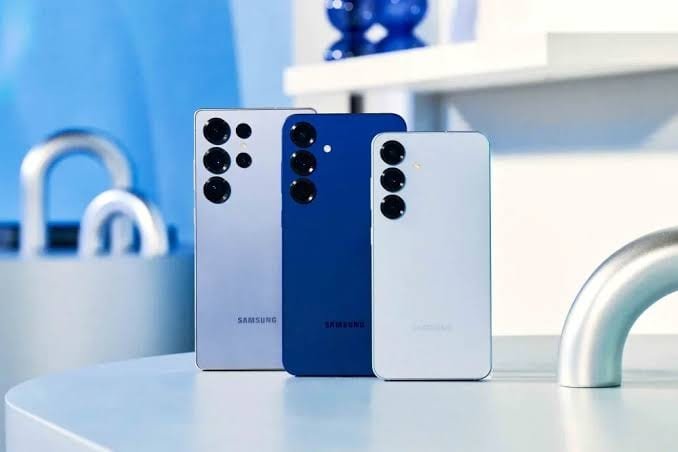 Três aparelhos da linha Galaxy S25 lado a lado sobre uma mesa, vistos por trás